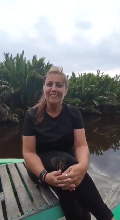 Guest sitting comfortably at the bow of the klotok with nipa palm riverbanks gliding by.